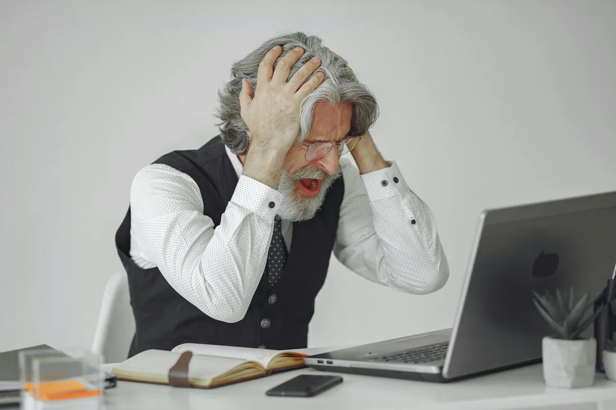 Empresário frustrado na frente do computador tentando usar IA sem resultado