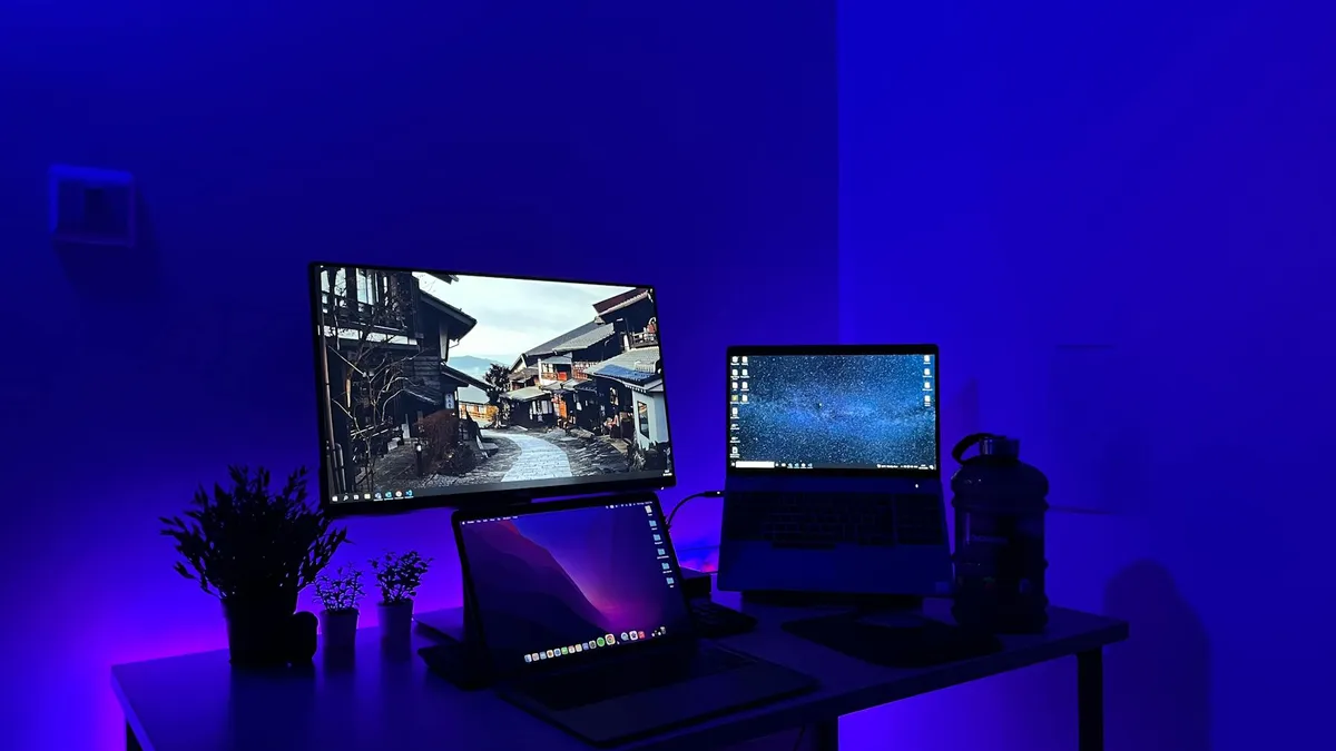 Três telas de computador lado a lado mostrando interfaces de IA diferentes em mesa de trabalho moderna